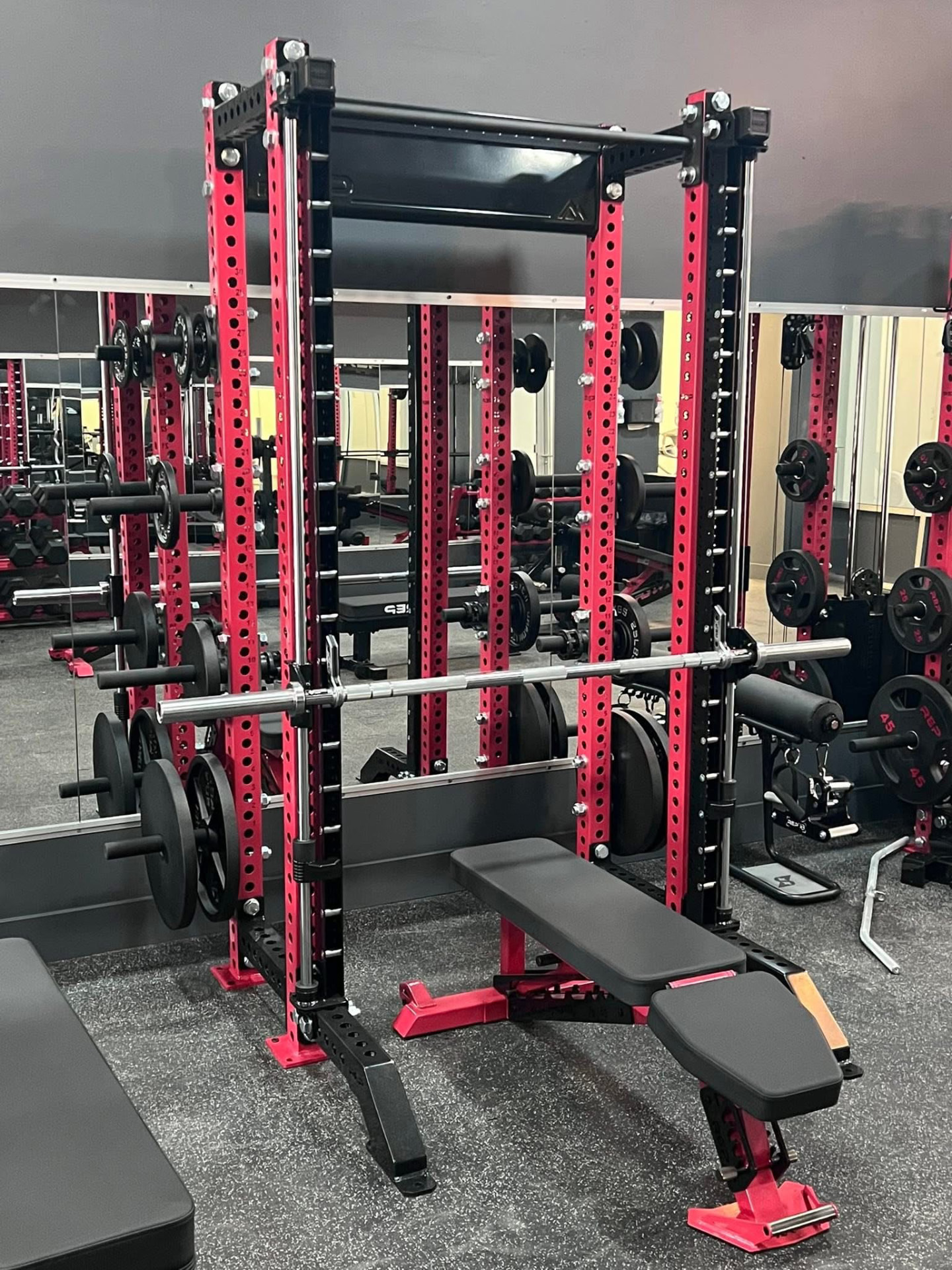 Red and black power rack with barbell and adjustable bench